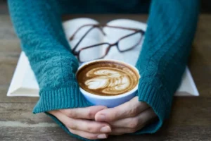 Xícara de café segurada com as mãos, remetendo à mesa de conversa do Aperitivos de Leitura